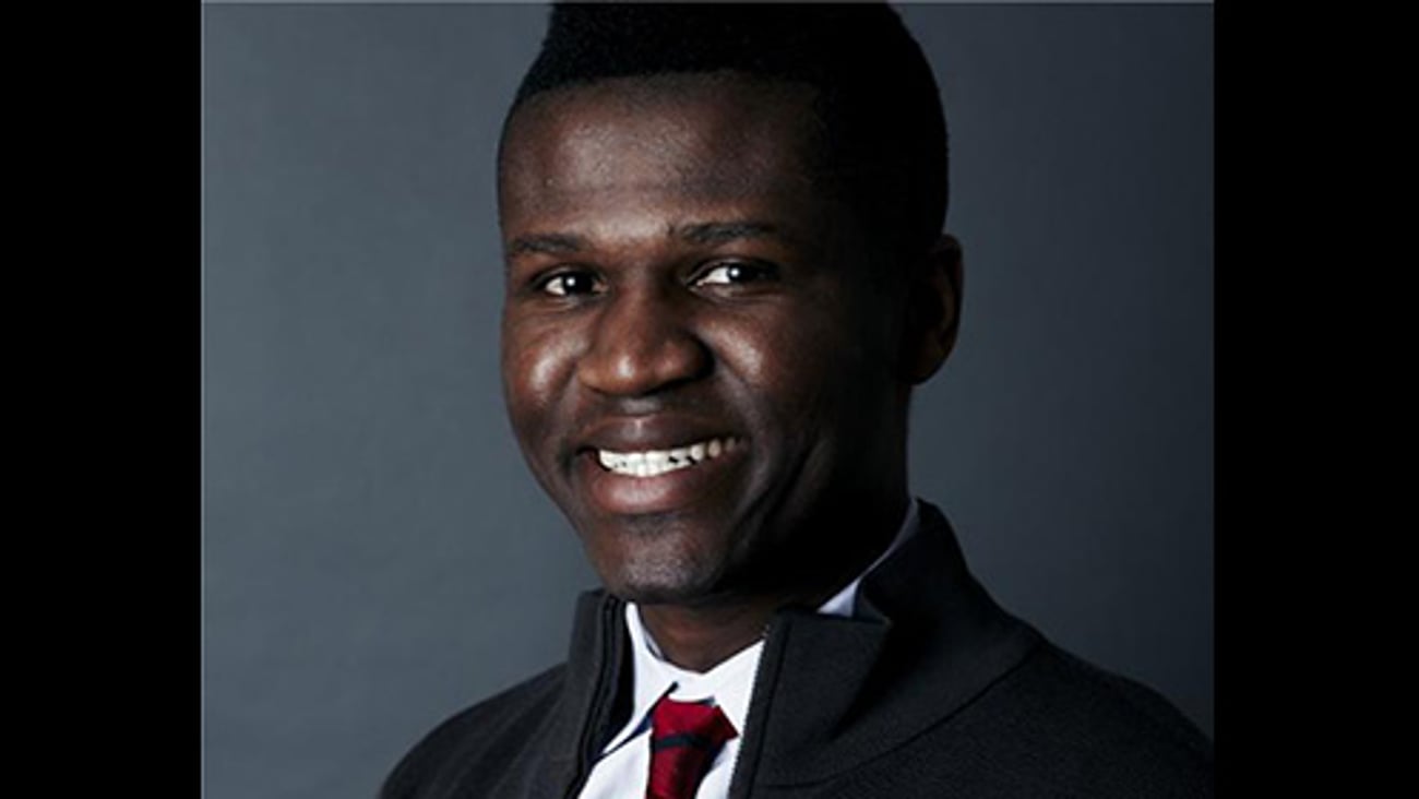 a man wearing a suit and tie smiling at the camera