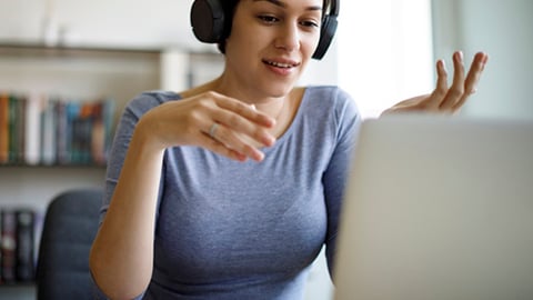 a woman sitting at a table with a laptop and smiling at the camera