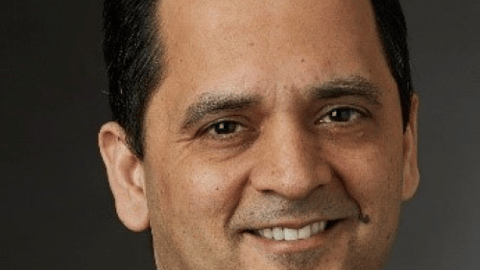 Sandeep Dadlani wearing a suit and tie smiling at the camera