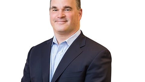 a man wearing a suit and tie smiling at the camera