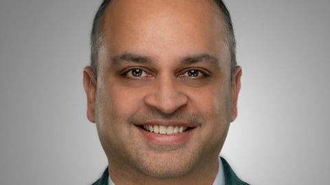 a man wearing a suit and tie smiling and looking at the camera