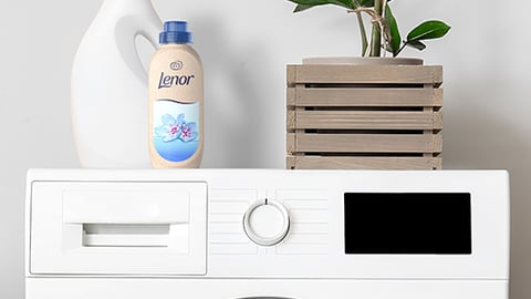 appliance,indoor,sitting,table,front,mirror,small,counter,sink,dryer,desk,computer,standing,holding,refrigerator,kitchen,man