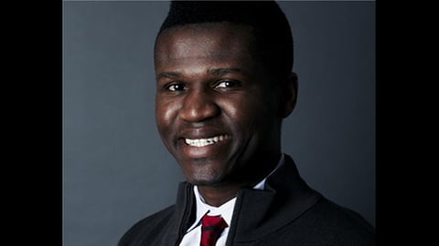 a man wearing a suit and tie smiling at the camera