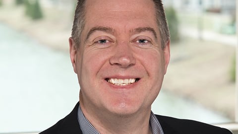 a man wearing a suit and tie smiling at the camera