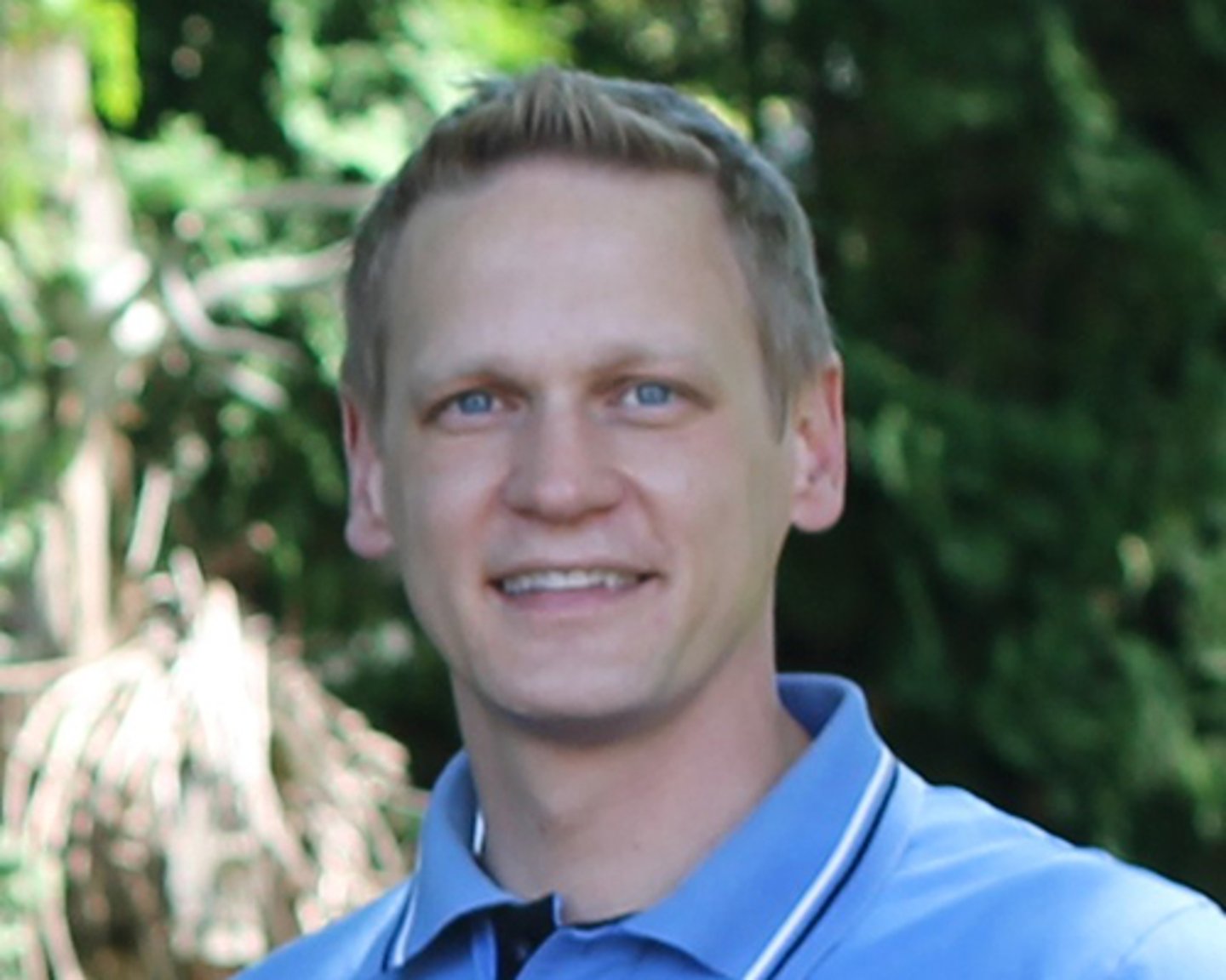 a man wearing a blue shirt and smiling at the camera