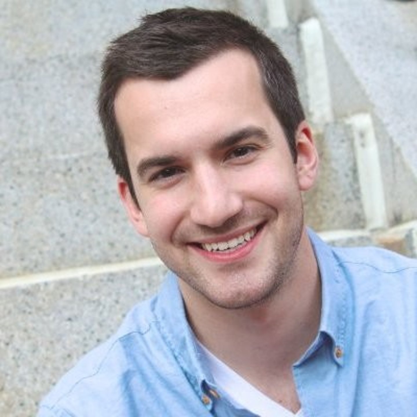 a man wearing a blue shirt and smiling at the camera