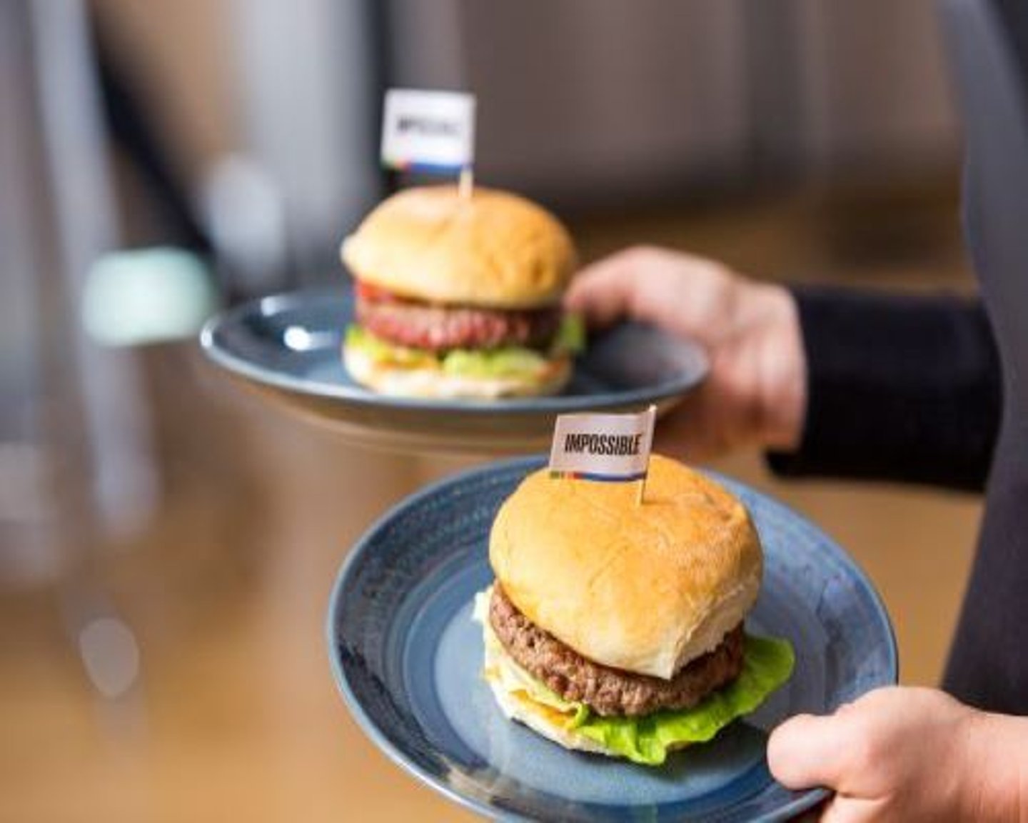 a person holding a plate of food on a table