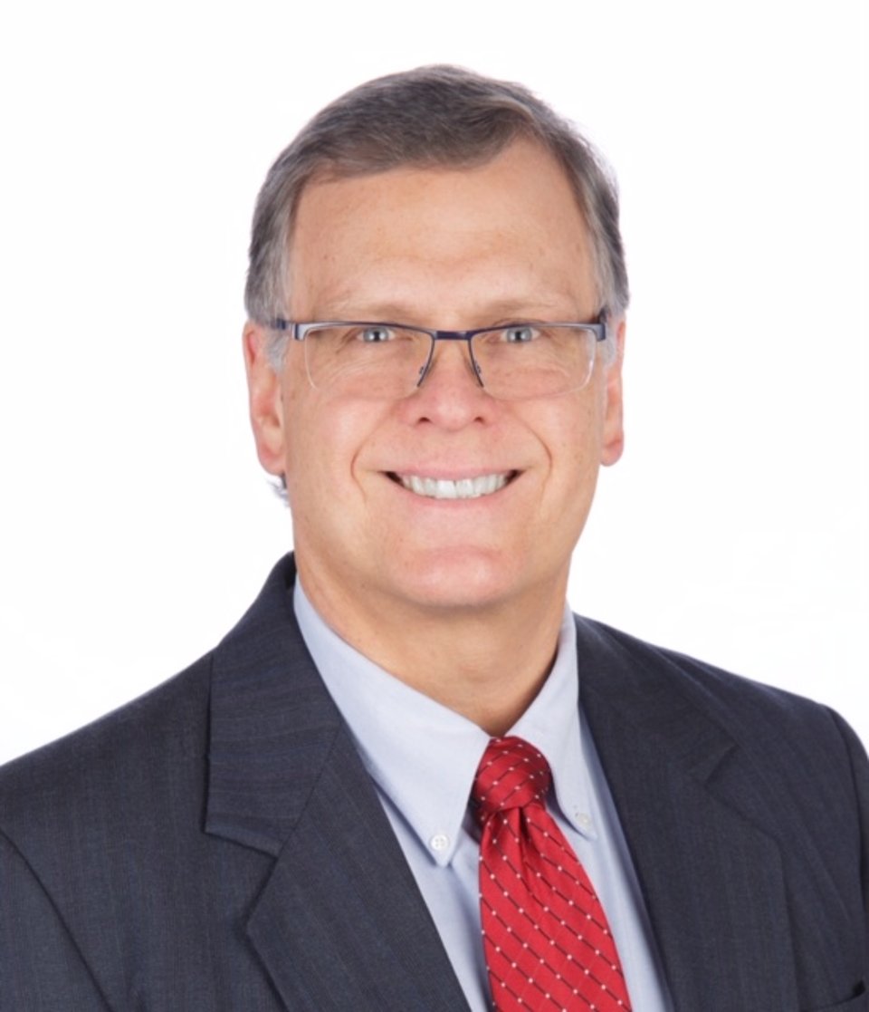 a man wearing a suit and tie smiling at the camera