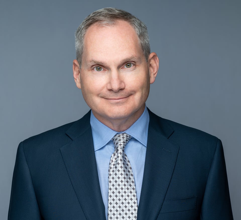 a man wearing a suit and tie smiling at the camera