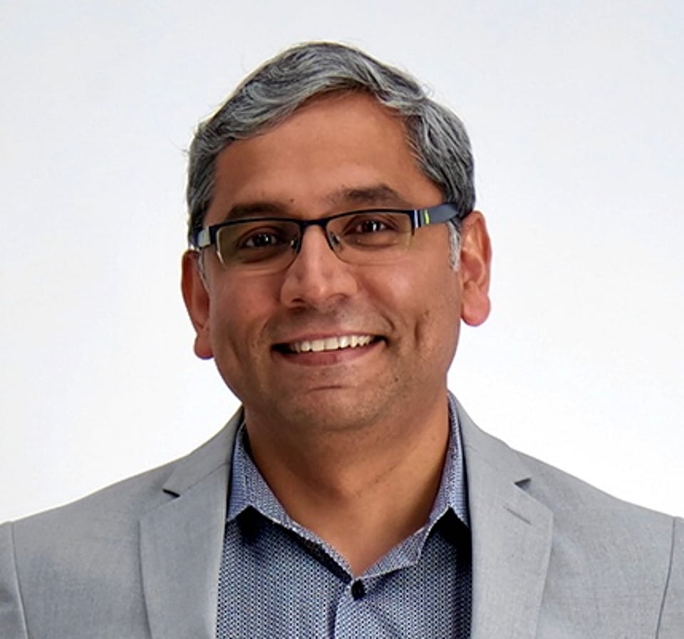 a man wearing glasses and smiling at the camera