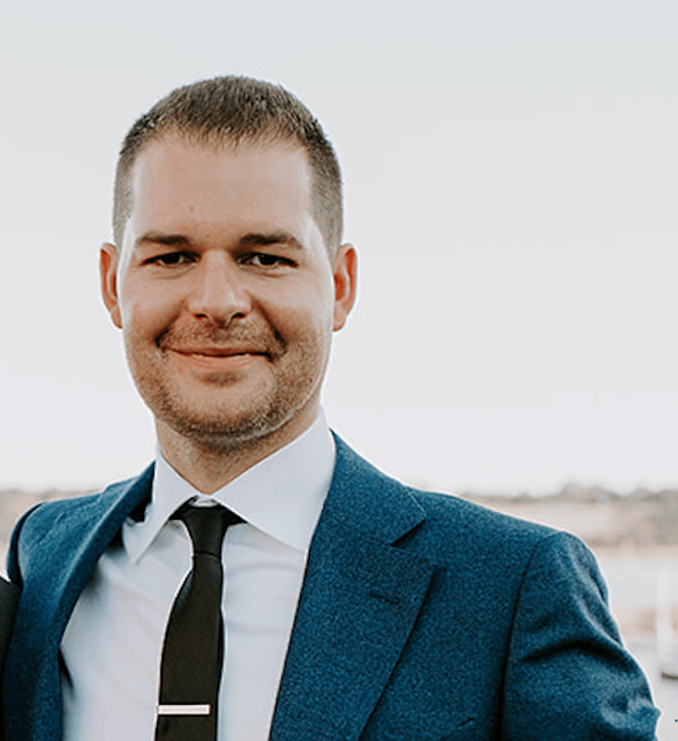 a man wearing a suit and tie smiling at the camera