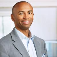 a man wearing a suit and tie smiling at the camera