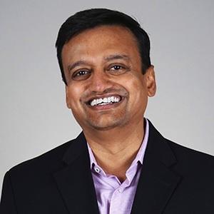 a man wearing a suit and tie smiling at the camera