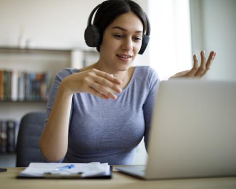 a woman sitting at a table with a laptop and smiling at the camera
