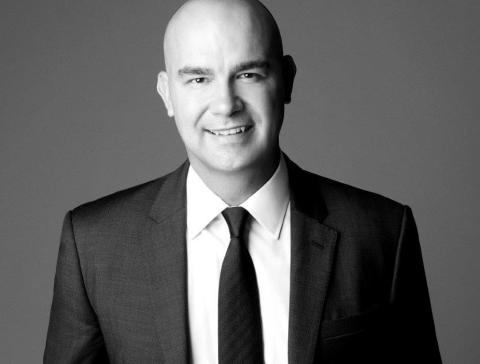 Andrew Stanleick wearing a suit and tie smiling at the camera