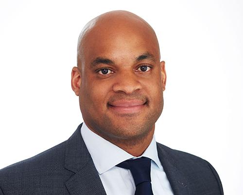 a man wearing a suit and tie smiling at the camera