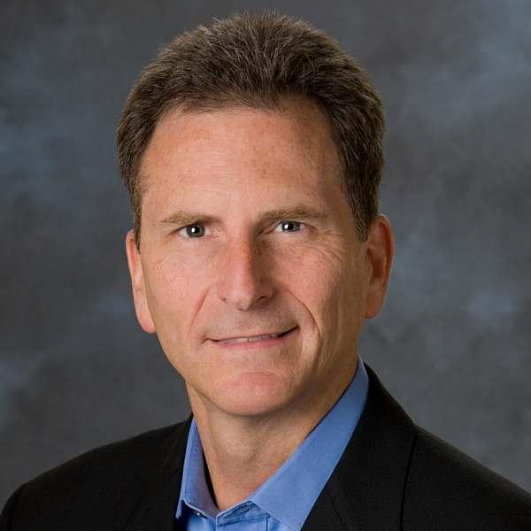 a man wearing a suit and tie smiling and looking at the camera