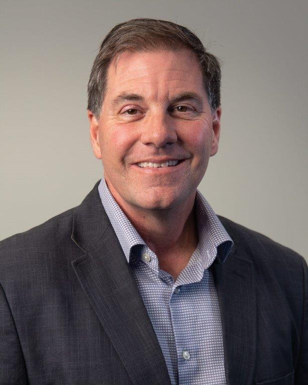 a man wearing a suit and tie smiling at the camera